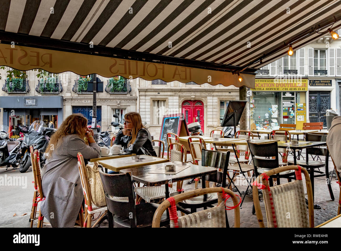 deux-femmes-assises-a-l-exterieur-a-une-table-dans-un-restaurant-parisien-de-st-georges-dans-le-9eme-arrondissementt-de-paris-france-rwe4hr